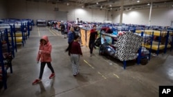 Migrants walk around bunk beds inside a government-run shelter in Ciudad Juarez, Mexico, on Sunday, Dec. 18, 2022. (AP Photo/Andres Leighton)