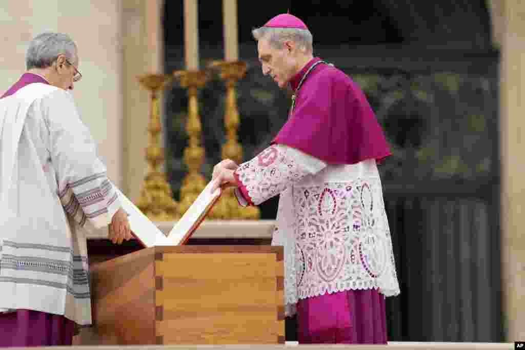 Archbishop Georg Ganswein, right, places the Book of the Gospels on top of the coffin of late Pope Emeritus Benedict XVI in St. Peter's Square at the Vatican, Jan. 5, 2023. 