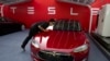 Seorang pekerja membersihkan sedan Tesla Model S di Beijing pada Rabu, 17 Oktober 2018. (Foto: AP)