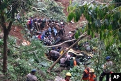 Tim penyelamat memindahkan rongsokan kendaraan yang rusak akibat tanah longsor yang dipicu gempa di Cianjur, Jawa Barat, Senin, 21 November 2022. (AP Photo/Rangga Firmansyah)