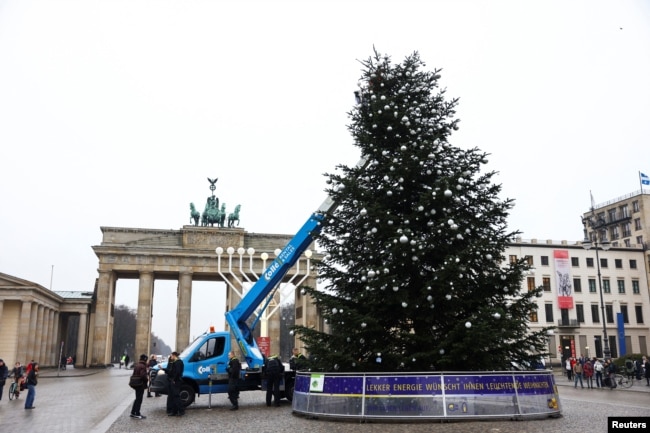 Para aktivis "Letzte Generation" (Generasi Terakhir) memotong pucuk pohon Natal di Gerbang Brandenburg, di Berlin, Jerman, 21 Desember 2022. (REUTERS/Christian Mang)