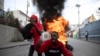 Manifestantes gritan consignas contra el gobierno frente a una barricada de neumáticos en llamas durante una protesta, el viernes 18 de noviembre de 2022, en Puerto Príncipe, Haití. 