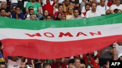 在伊朗对英格兰的比赛赛场上，伊朗观众手举印有抗议标语“女性”的抗议旗帜。（2022年11月21日）