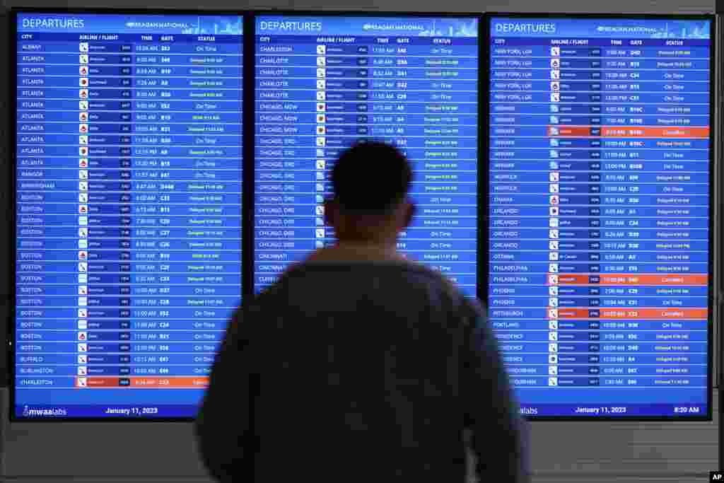 Патник гледа во табла за откажани летови на националниот аеродром Вашингтон Роналд Реган во Арлингтон, Вирџинија. Летовите се одложуваа на повеќе локации низ САД по прекин на компјутерот во Федералната управа за авијација.