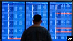 A traveler looks at a flight board with delays and cancelations at Ronald Reagan Washington National Airport in Arlington, Virginia.&nbsp;Flights are being delayed at multiple locations across the United States after a computer outage at the Federal Aviation Administration.