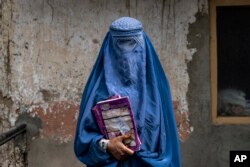 FILE - Arefeh, a 40-year-old Afghan woman, leaves an underground school, in Kabul, Afghanistan, Saturday, July 30, 2022. (AP Photo/Ebrahim Noroozi, File)