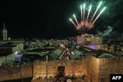 Kembang api menerangi langit saat warga menghadiri penyalaan pohon Natal di Gerbang Jaffa, kota tua Yerusalem, 11 Desember 2022. (AHMAD GHARABLI/AFP)