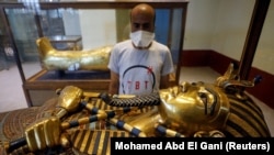 Seorang turis melihat peti mati firaun kuno Raja Tutankhamen saat ia mengunjungi Museum Mesir di alun-alun Tahrir setelah dibuka kembali setelah wabah COVID-19, di Kairo, Mesir, 1 Juli 2020. (Foto: REUTERS/Mohamed Abd El Gani)