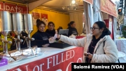 ARCHIVO - Latinas trabajan vendiendo platos y dulces típicos de América Latina al público del Downtown Holiday Market en Washington.