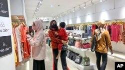 Warga mengenakan masker saat melihat-lihat pakaian di sebuah pusat perbelanjaan di Jakarta, Jumat, 30 Desember 2022. (AP/Tatan Syuflana)