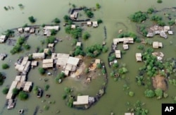 FILE - Homes are surrounded by floodwaters in Sohbat Pur city, a district of Pakistan's southwestern Baluchistan province, Aug. 30, 2022.