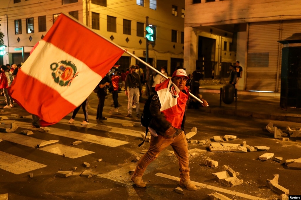 Un manifestante lleva la bandera de Perú durante una protesta exigiendo la disolución del Congreso y celebrar elecciones democráticas en lugar de reconocer a Dina Boluarte como presidenta de Perú, tras la destitución del líder peruano Pedro Castillo, en Lima, el 11 de diciembre de 2022. 