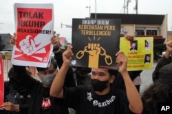 Aktivis mengangkat poster selama berlangsungnya aksi unjuk rasa menentang RKUHP di Yogyakarta, Selasa, 6 Desember 2022. (AP Photo/Slamet Riyadi)