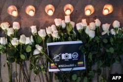 Bunga, lilin, dan papan bertuliskan "Tidak satu pun lagi" terlihat saat pemakaman jurnalis El Comercio Ekuador Javier Ortega, fotografer Paul Rivas, dan pengemudi Efrain Segarra di Cali, Kolombia pada 26 Juni 2018. (Foto: AFP)