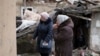 Anhelina, right, watches as emergency workers remove debris of her house, destroyed following a Russian missile attack in Kyiv, Ukraine, Dec. 29, 2022. 
