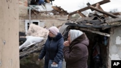 Anhelina, right, watches as emergency workers remove debris of her house, destroyed following a Russian missile attack in Kyiv, Ukraine, Dec. 29, 2022. 