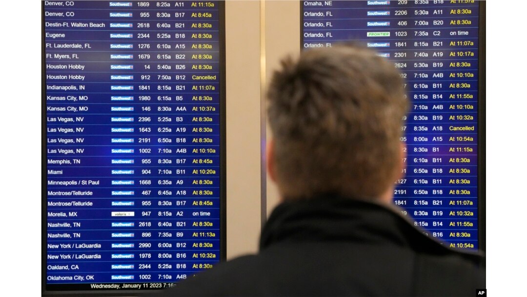 Steve Gasser dari Chicago melihat layar informasi penerbangan di Bandara Midway Chicago yang melaporkan penundaan penerbangan akibat gangguan pada komputer FAA di Administrasi Penerbangan Federal, yang menyebankan terdundanya penerbangan di seluruh AS Rabu, 11 Januari 2023. (AP/Charles Rex Arbogast)