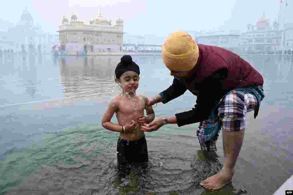 A young Sikh devotee takes a bath in the holy Sarovar, or pool, to prepare for birth anniversary celebrations of the 10th Guru of the Sikhs, Guru Gobind Singh, at the Golden Temple in Amritsar, India.