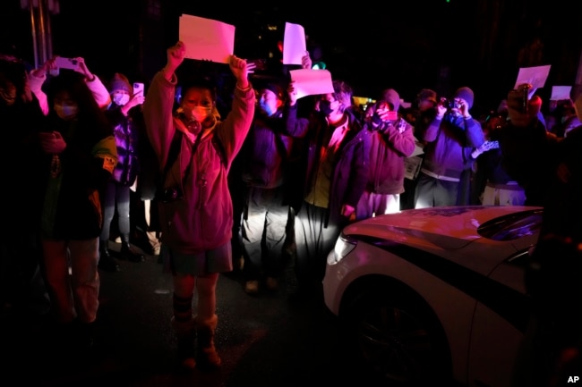 Protesters hold up blank papers and chant slogans as they march in protest in Beijing, Sunday, Nov. 27, 2022. (AP Photo/Ng Han Guan)