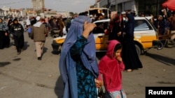 FILE - An Afghan woman and a girl walk in a street in Kabul, Afghanistan, November 9, 2022. 