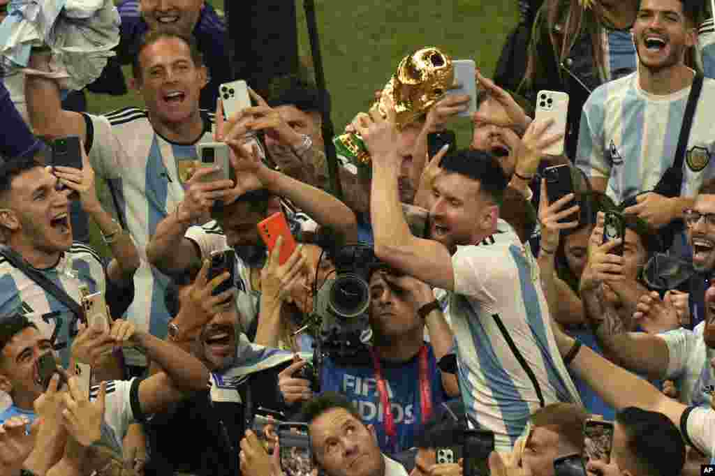 O argentino Lionel Messi segura o troféu vencedor ao comemorar com os fãs depois de a Argentina ter ganho a final do Campeonato do Mundo de futebol contra a França no Estádio Lusail, em Lusail, Qatar, 18 de Dezembro de 2022.