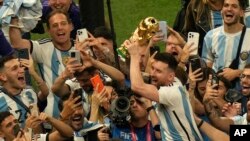 Argentina's Lionel Messi holds the winners trophy as he celebrates with fans after Argentina won the World Cup final soccer match against France at the Lusail Stadium in Lusail, Qatar, Dec. 18, 2022. 