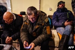A local resident looks at his mobile phone as he and others rest in a humanitarian aid center in Bakhmut, Donetsk region, Jan. 6, 2023, as the Russia-Ukraine war enters its 316th day.