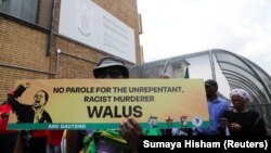 FILE: A protester holds a placard during a demonstration against the parole of Janusz Walus who murdered anti-apartheid leader Chris Hani in 1993, outside the Kgosi Mampuru II Correctional Centre in Pretoria, South Africa, November, 30, 2022