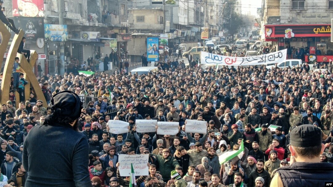Anqara va Damashqning ehtimoliy yaqinlashuviga qarshi Suriya muxolifati bayroqlari va plakatlar bilan norozilik namoyishiga chiqqan odamlar. Suriya, 30-dekabr, 2022.
