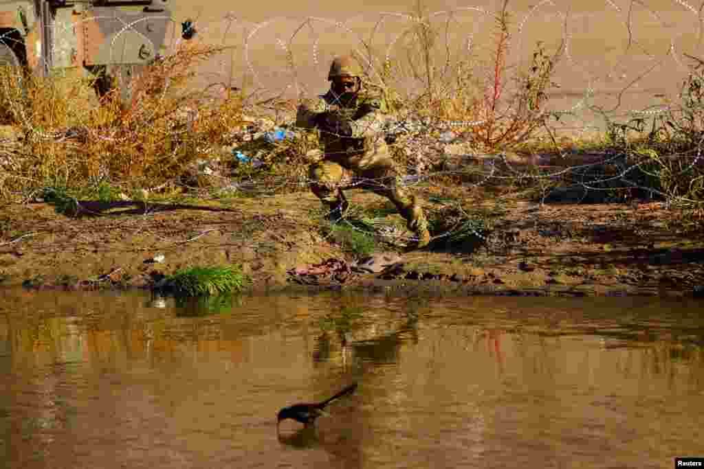 A member of the Texas National Guard places wire fence on the banks of the Rio Bravo river, the border between the United States and Mexico, to reinforce border security and inhibiting the crossing of migrants into the United States, seen from Ciudad Juarez, Mexico.