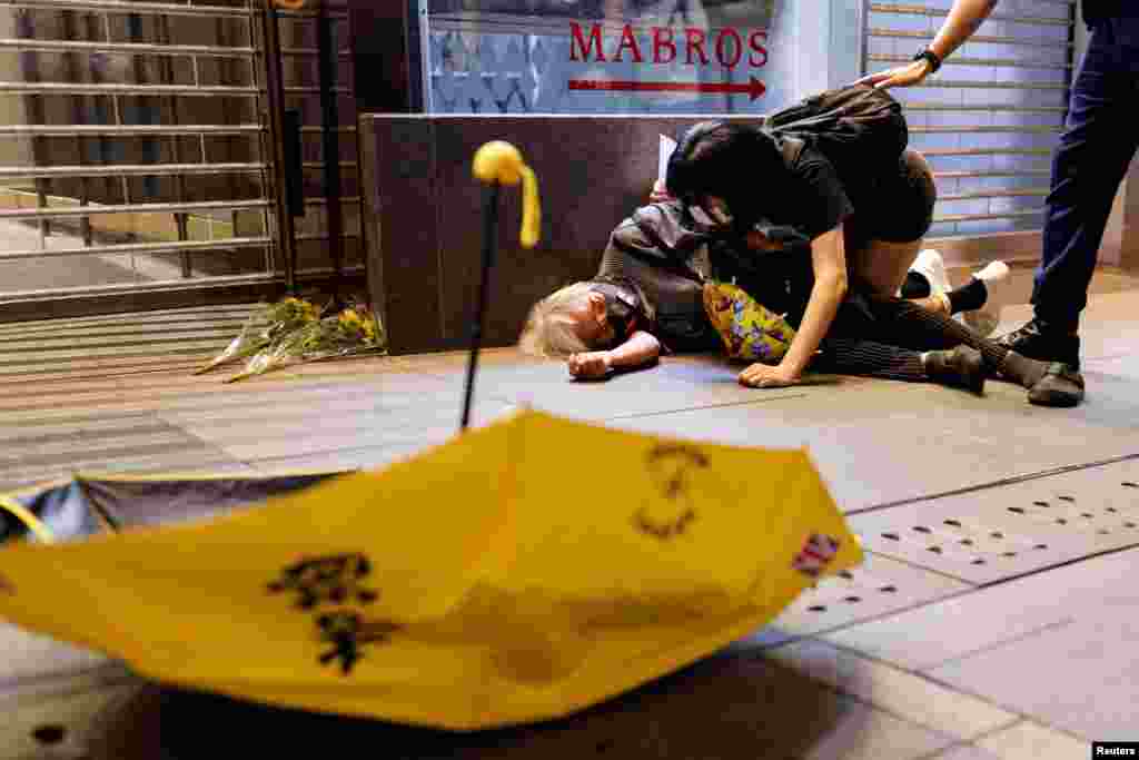 A protester lies on the ground after being pushed during a protest in Hong Kong, over COVID-19 restrictions in mainland China, during a commemoration of the victims of a fire in Urumqi.