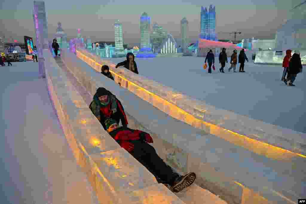 People slide down in an ice slide at the Harbin Ice and Snow World in Harbin, in China&#39;s northeastern Heilongjiang province, during the opening ceremony of the 39th Harbin China International Ice and Snow Festival.