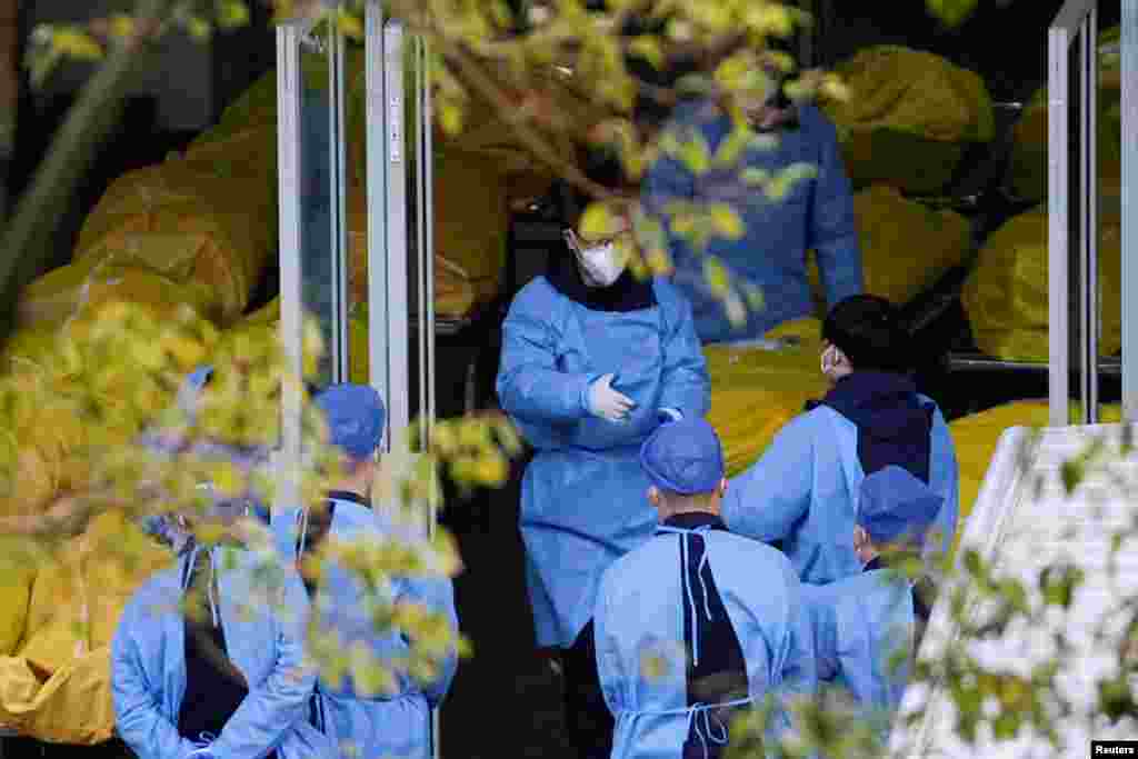 Работници покрај неколку вреќи со мртви тела на погребна куќа, додека епидемиите на ковид-19 продолжува во Шангај, Кина.