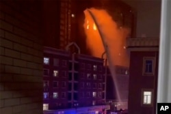 In this image taken from video, firefighters spray water on a fire at a residential building in Urumqi in western China's Xinjiang Uyghur Autonomous Region, Nov. 24, 2022.