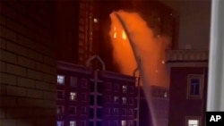 在這張從視頻截屏的圖像中，2022 年 11 月 24 日，消防員在中國西部新疆維吾爾自治區烏魯木齊市的一棟燃起大火的住宅樓噴水滅火。