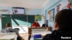 A teacher conducts a hybrid mathematic lesson for junior students of a private school amid Russia's attack on Ukraine, in Kyiv, Ukraine, Dec. 1, 2022.