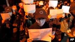 Protesters hold up blank papers and chant slogans as they march in Beijing, Nov. 27, 2022. 