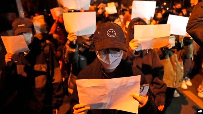 Protesters hold up blank papers and chant slogans as they march in Beijing, Nov. 27, 2022.