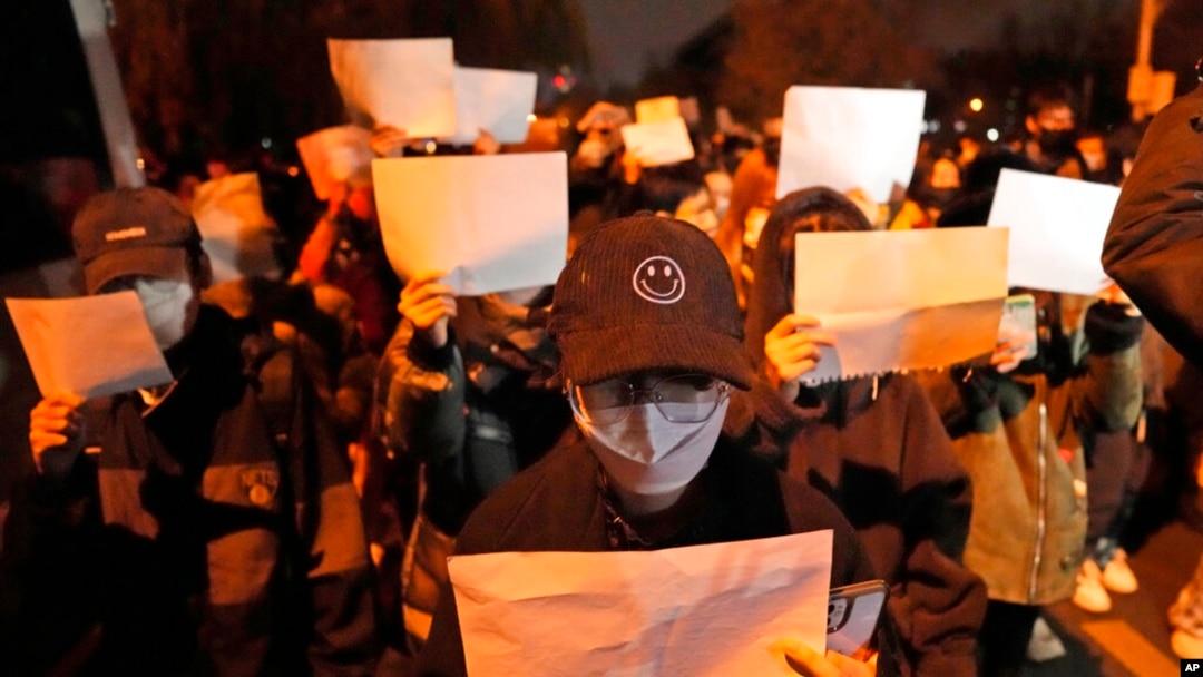 Protesters hold up blank papers and chant slogans as they march in Beijing, Nov. 27, 2022.