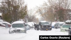 Seseorang menggunakan sekop untuk menggali mobilnya yang tertahan di tengah jalan saat badai salju menghantam kawasan Buffalo di Buffalo, New York, AS, 19 November 2022. (Foto: REUTERS/Carlos Osorio)