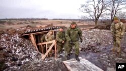 FILE - Russian Defense Minister Sergei Shoigu, center, walks out of a trench, escorted by a group of officers as he inspects Russian troops at an undisclosed location in Ukraine, Dec. 22, 2022.. 