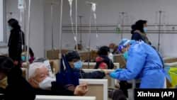上海一家医院的医护人员正在帮助一名病人打点滴。（2023年1月5日）
