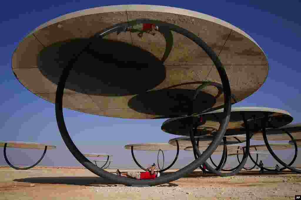 A man takes pictures at the Olafur Eliasson's Circular Mirror Installation near Al-Ruwais, in north Doha, Qatar.