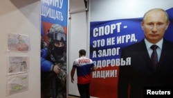 A man walks past a banner with the portrait of Russian President Vladimir Putin at the sports and patriotic club "Yaropolk" in Krasnogorsk outside Moscow, Dec. 3, 2022. The banner reads: "Sport is not a game, but the guarantee of a nation's health!" 
