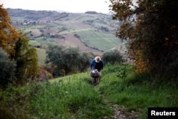 Fabrizio Cardinali, 72, carries an oil container from his house in the woods of the small town of Cupramontana, Ancona, Marche, Italy, December 12, 2022. (REUTERS/Yara Nardi)