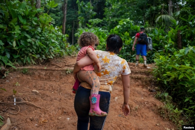La migrante venezolana, Macyuli, sostiene a su hija mientras cruza el tapón del Darién junto a otros compatriotas.