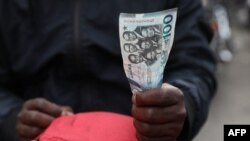 FILE: A man holds a 100 cedis, the Ghana currency, note in Accra, Ghana, on December 1, 2022. - Ghana is battling its worst economic crisis in decades.
