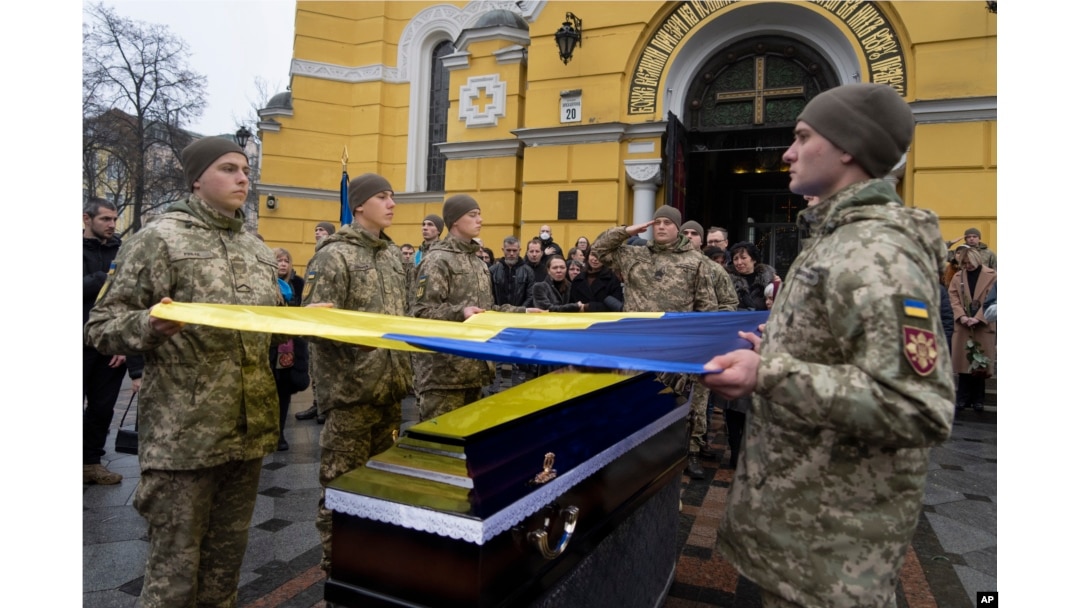Prajurit Ukraina mengibarkan bendera di atas peti mati rekan mereka saat upacara pemakaman Volodymyr Yezhov yang tewas di medan perang di Katedral St. Volodymyr di Kyiv, Ukraina, Selasa, 27 Desember 2022. (AP/Efrem Lukatsky)