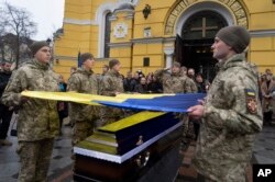 Prajurit Ukraina mengibarkan bendera di atas peti mati rekan mereka saat upacara pemakaman Volodymyr Yezhov yang tewas di medan perang di Katedral St. Volodymyr di Kyiv, Ukraina, Selasa, 27 Desember 2022. (AP/Efrem Lukatsky)