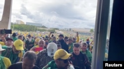 Supporters ofÊBrazil's former President Jair Bolsonaro walk through a flooded office during aÊprotest against President Luiz Inacio Lula da Silva in Brasilia,ÊBrazil January 8, 2023 in this screen grab obtained from a social media video. (George Marques/via REUTERS)